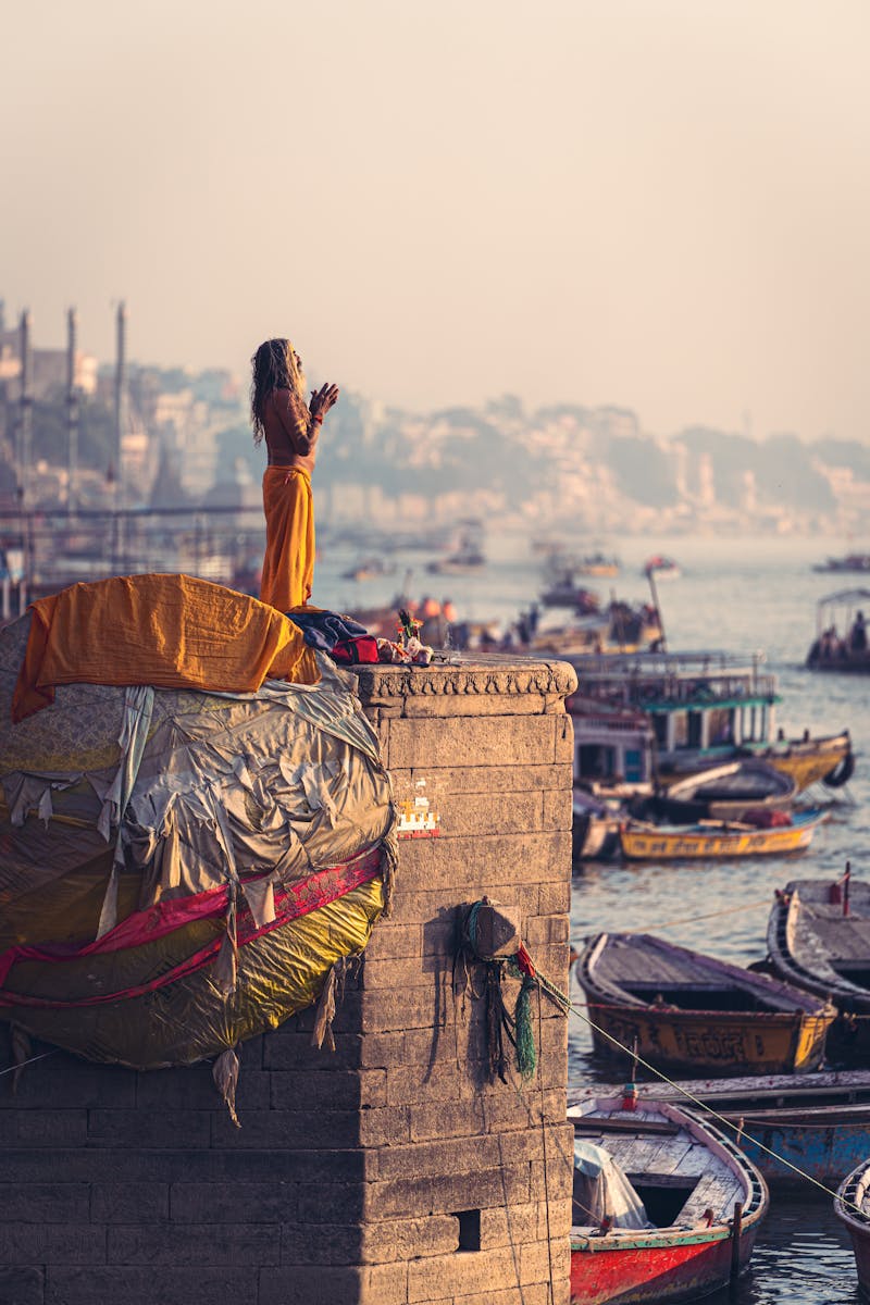 A person performs a morning ritual on Varanasi Ghat, surrounded by the serene Ganges River.